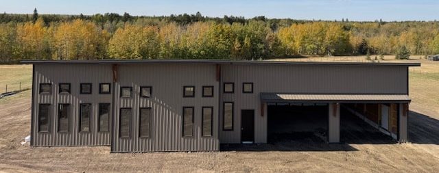 A buckskin post-frame Prairie Peak with soffits, closed lean-tos, and overhead doors
