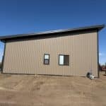 A buckskin post-frame Prairie Peak with soffits, closed lean-tos, and overhead doors