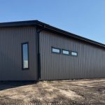 A buckskin post-frame Prairie Peak with soffits, closed lean-tos, and overhead doors