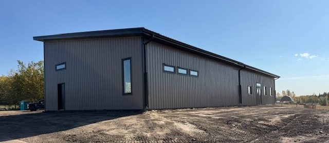 A buckskin post-frame Prairie Peak with soffits, closed lean-tos, and overhead doors
