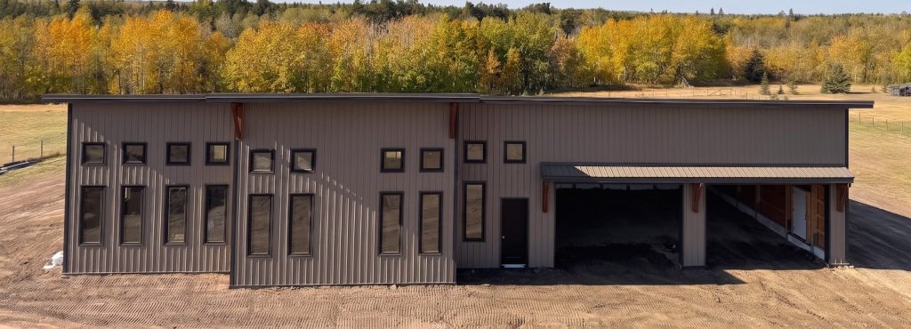 A buckskin post-frame Prairie Peak with soffits, closed lean-tos, and overhead doors
