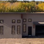 A buckskin post-frame Prairie Peak with soffits, closed lean-tos, and overhead doors