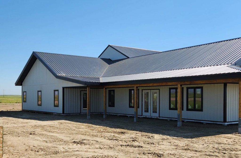 A white white post-frame custom residential build with soffits, open lean-to porch, and overhead doors