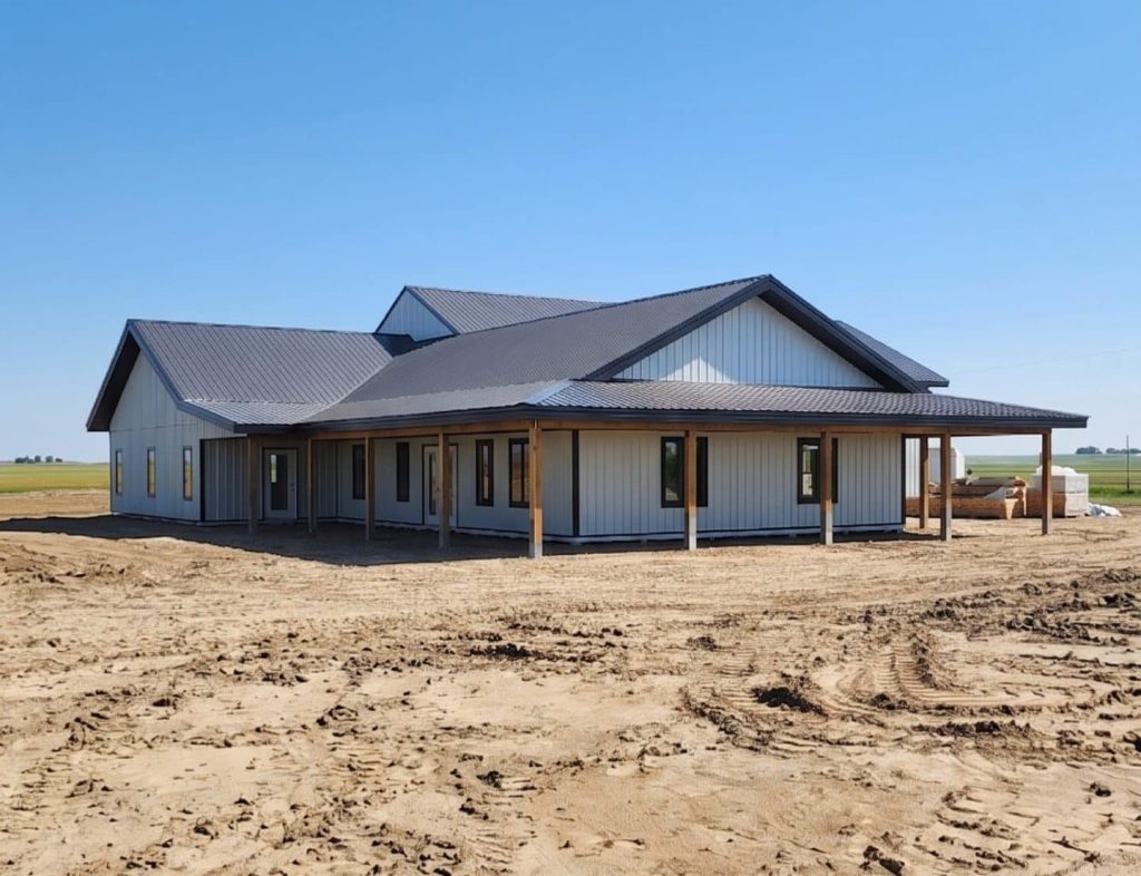 A white white post-frame custom residential build with soffits, open lean-to porch, and overhead doors