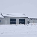 A white white post-frame Shouse with three overhead doors, two open lean-tos and soffits
