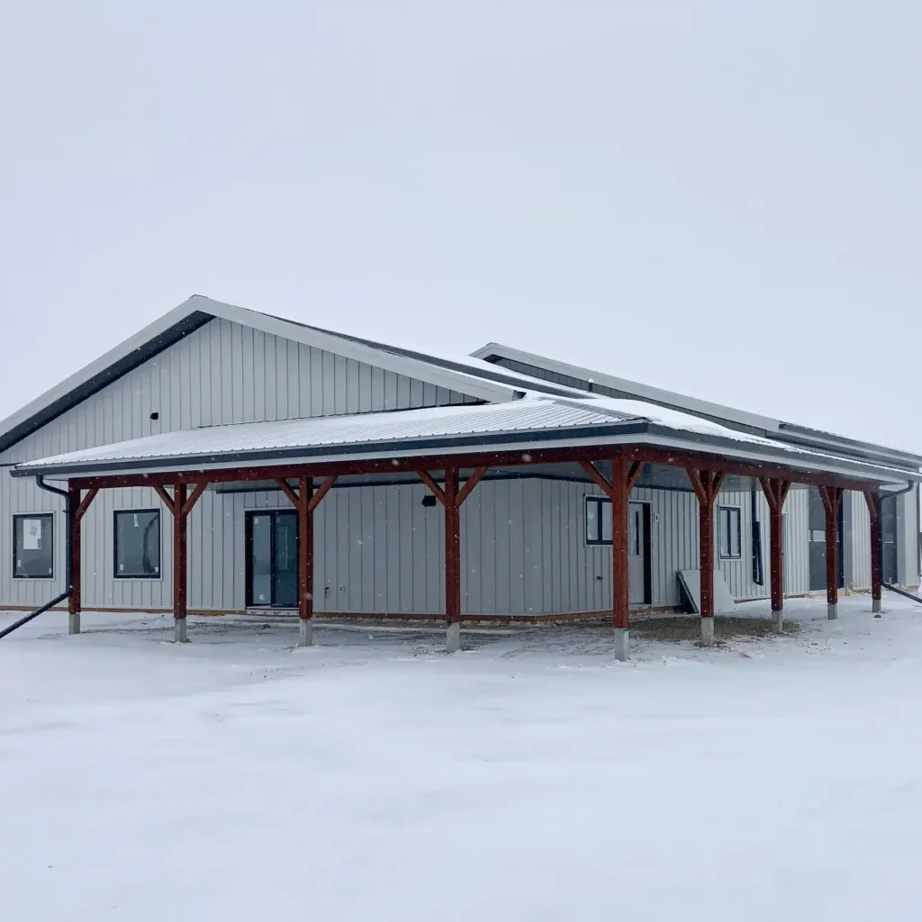 A white white post-frame Shouse with three overhead doors, two open lean-tos and soffits