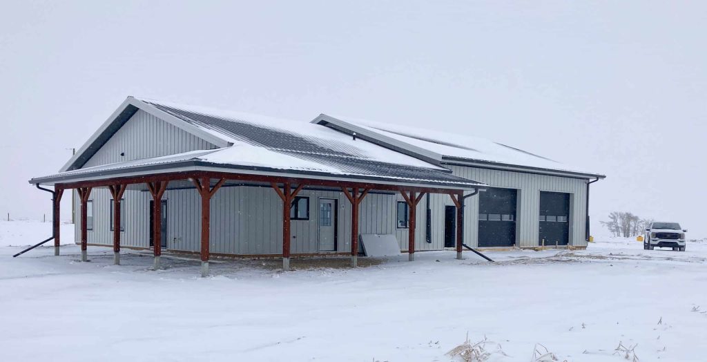 A white white post-frame Shouse with three overhead doors, two open lean-tos and soffits