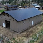 A buckskin post-frame equestrian barn with timber accents, soffits, and a overhead door