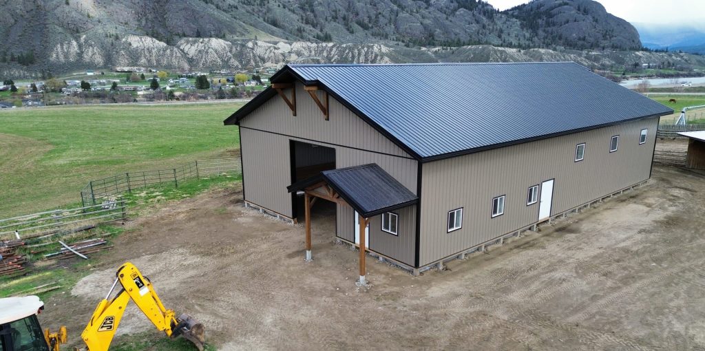 A buckskin post-frame equestrian barn with timber accents, soffits, and a overhead door