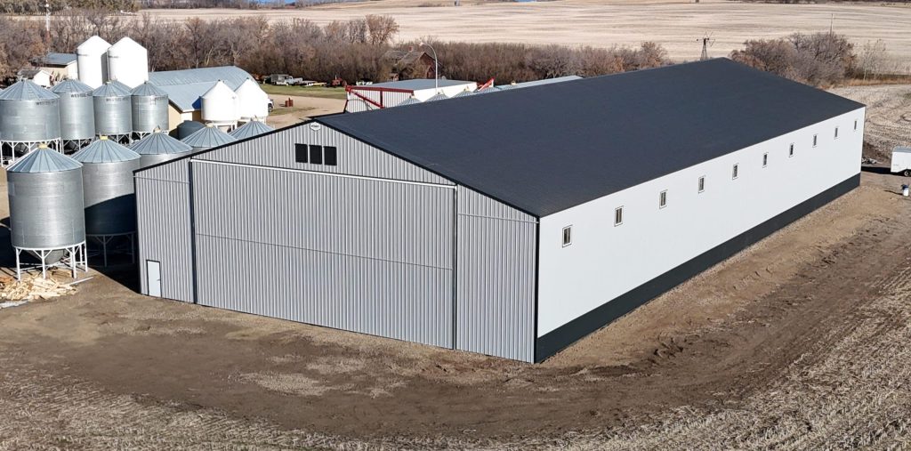 A ascot grey post-frame agricultural storage building with two bi-fold doors and wainscoting