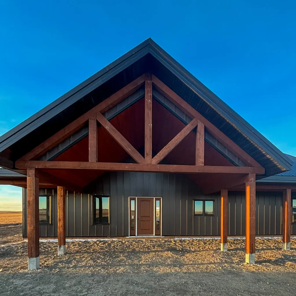 A coffee brown post-frame barndominium with three overhead doors, timber accents, soffits, and open and closed lean-tos