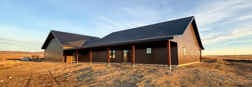 A coffee brown post-frame barndominium with three overhead doors, timber accents, soffits, and open and closed lean-tos