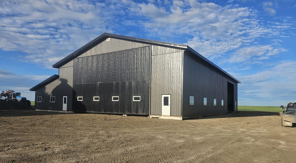A charcoal post-frame agricultural shop with a closed lean-to, a bi-fold and overhead door
