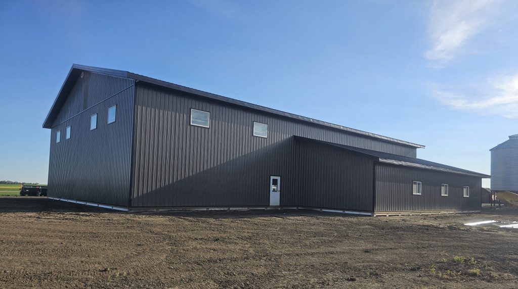 A charcoal post-frame agricultural shop with a closed lean-to, a bi-fold and overhead door