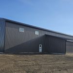 A charcoal post-frame agricultural shop with a closed lean-to, a bi-fold and overhead door