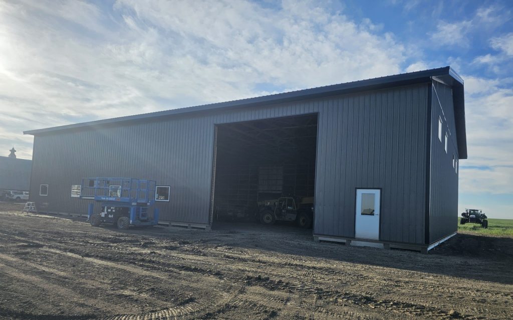 A charcoal post-frame agricultural shop with a closed lean-to, a bi-fold and overhead door