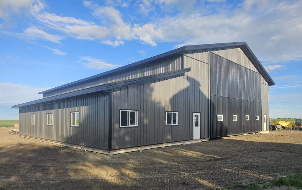 A charcoal post-frame agricultural shop with a closed lean-to, a bi-fold and overhead door