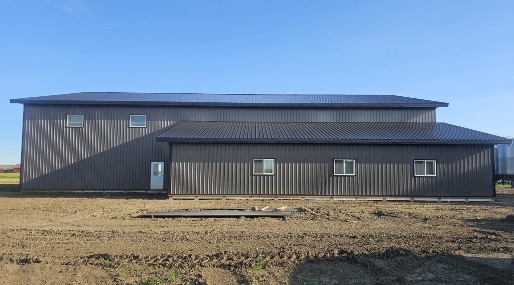 A charcoal post-frame agricultural shop with a closed lean-to, a bi-fold and overhead door