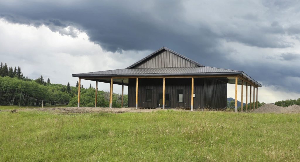 A coffee brown post-frame agricultural shop with wrap around open lean-to and overhead doors