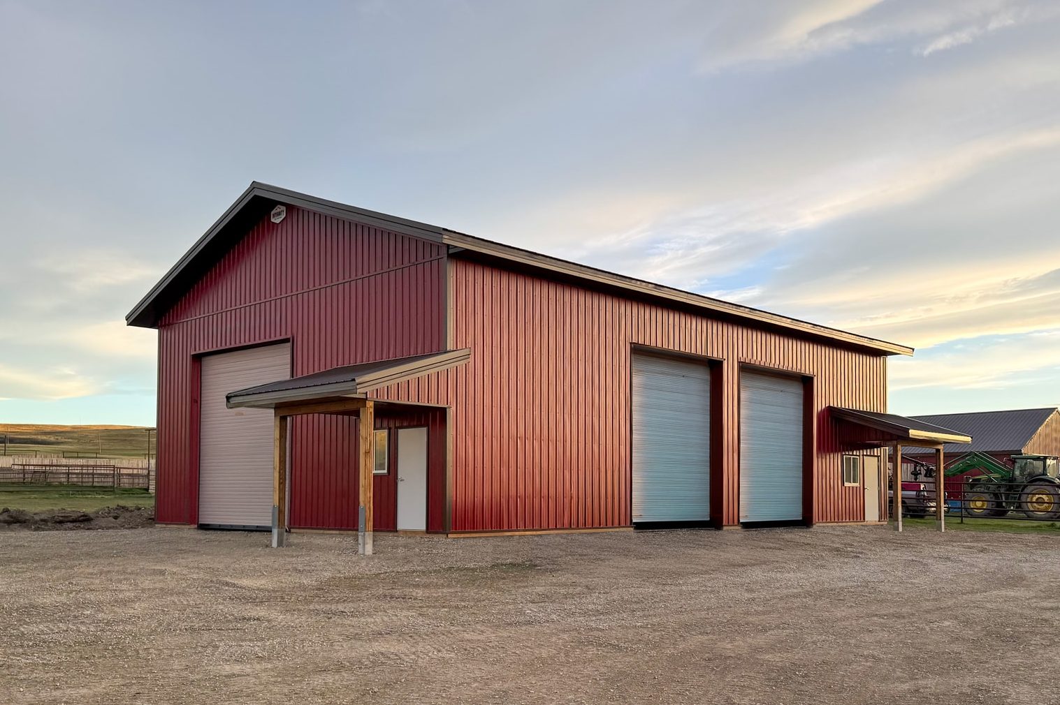 A dark red post-frame lifestyle & hobby shop with soffits, two open lean-tos, and three overhead doors