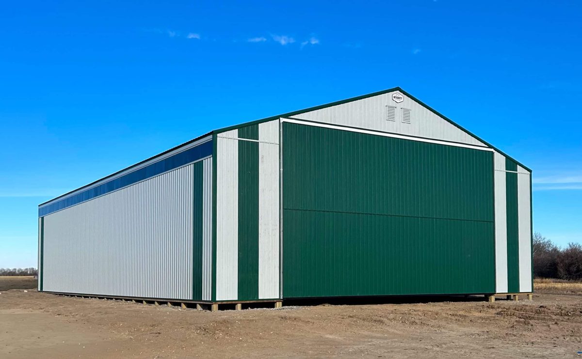A bone white post-frame agricultural machine shed with a melchers green roof