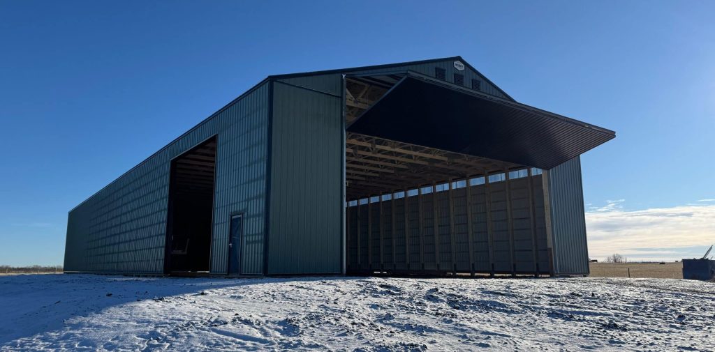 A dark sage post-frame machine shed with sliding doors, overhead doors, and bi-fold doors