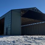 A dark sage post-frame machine shed with sliding doors, overhead doors, and bi-fold doors