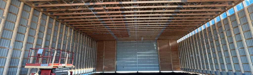 A dark sage post-frame machine shed with sliding doors, overhead doors, and bi-fold doors