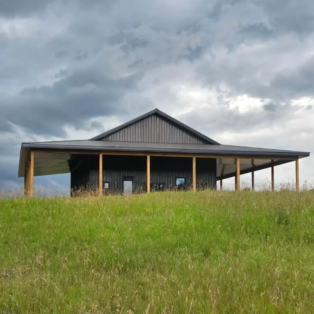 A coffee brown post-frame agricultural shop with wrap around open lean-to and overhead doors