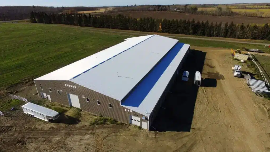 A buckskin post-frame riding arena with two overhead doors