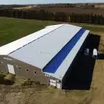 A buckskin post-frame riding arena with two overhead doors