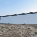 A bright white post-frame agricultural storage building with bi-fold and overhead doors