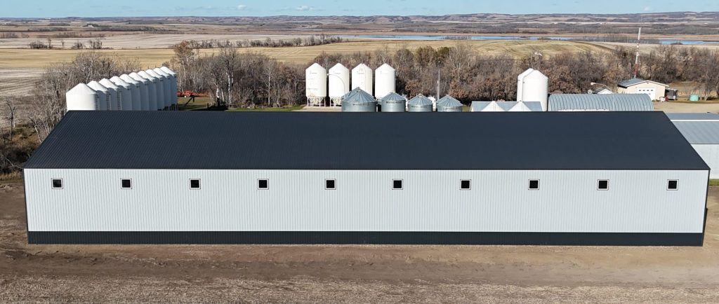 A ascot grey post-frame agricultural storage building with two bi-fold doors and wainscoting