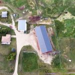 A dark red post-frame riding arena with a chain overhead door