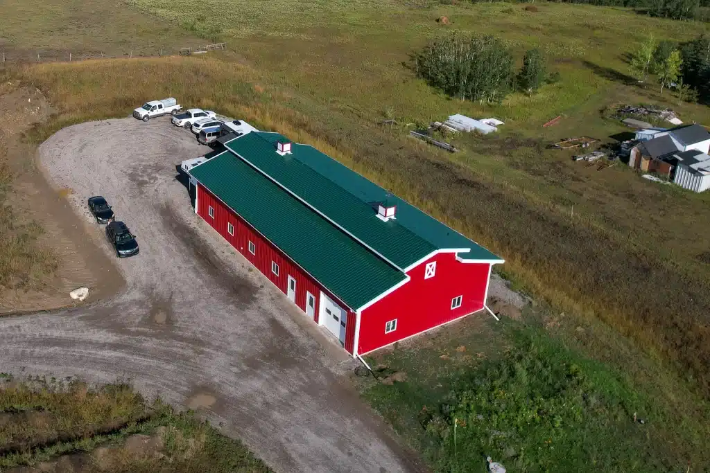 A dark red post-frame equestrian barn