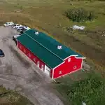 A dark red post-frame equestrian barn
