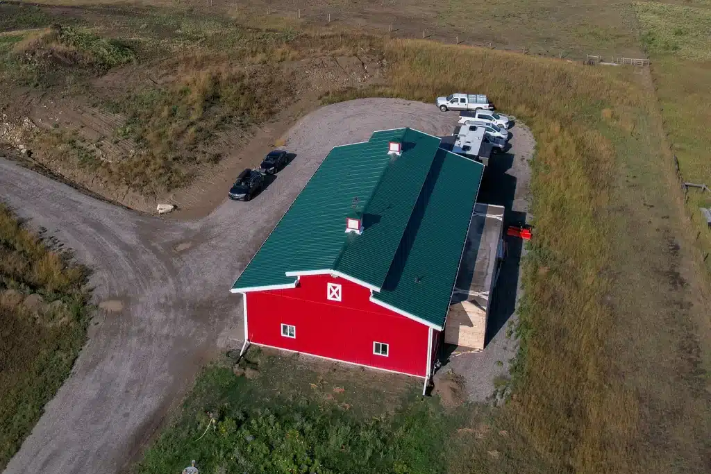 A dark red post-frame equestrian barn