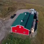 A dark red post-frame equestrian barn