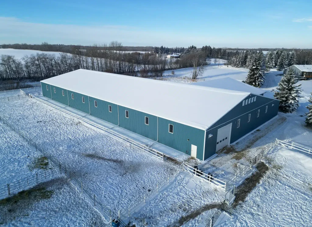 A slate blue post-frame equestrian riding arena