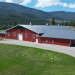 A tile red post-frame riding arena with overhead doors, timber accents, and soffits