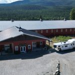 A tile red post-frame riding arena with overhead doors, timber accents, and soffits
