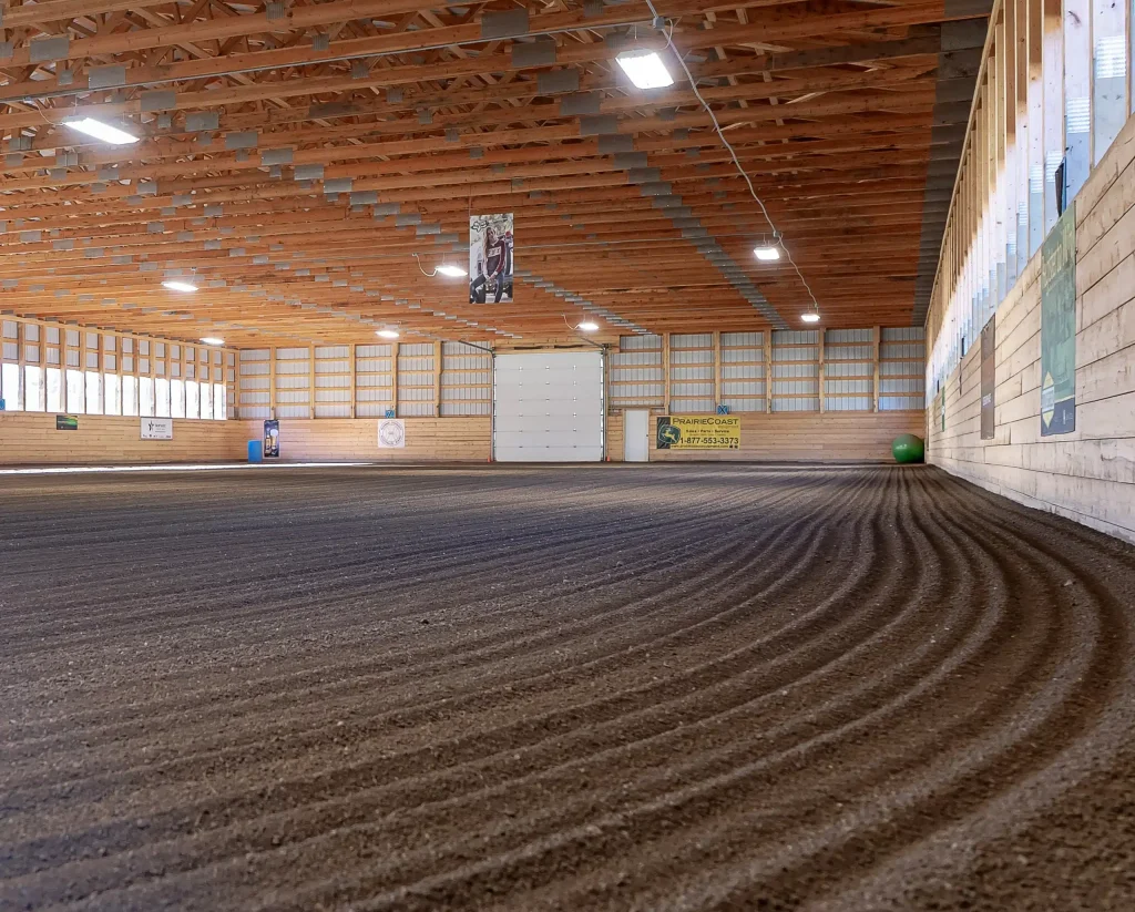 A dark sage post-frame equestrian Riding Arena with overhead doors and skylight