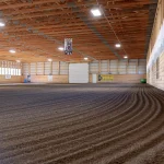 A dark sage post-frame equestrian Riding Arena with overhead doors and skylight