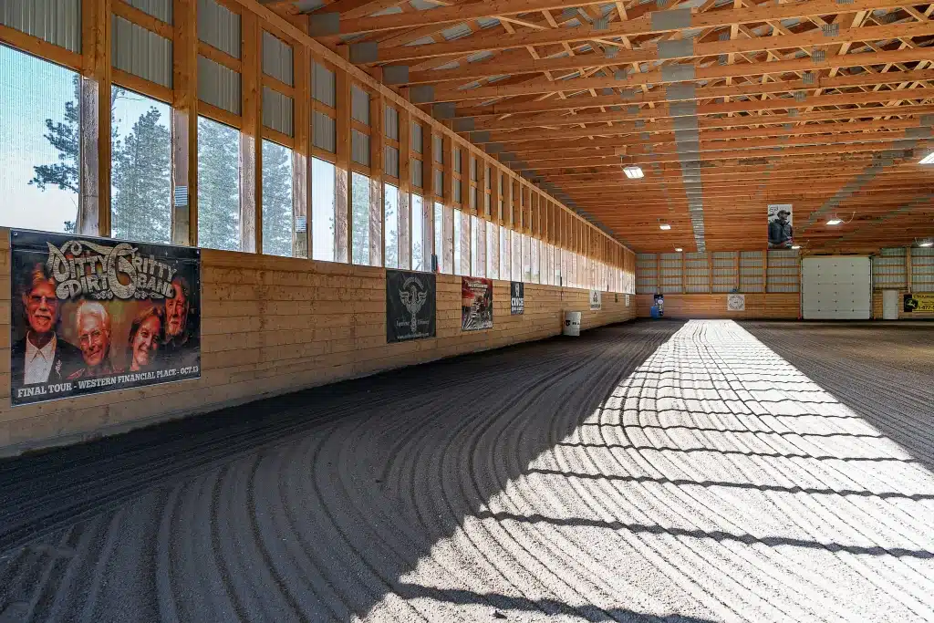 A dark sage post-frame equestrian Riding Arena with overhead doors and skylight