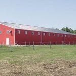 A bright red post-frame riding arena with overhead doors