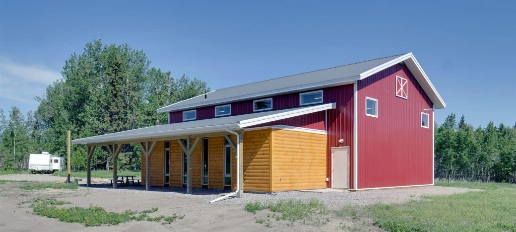 A dark red post-frame equestrian barn
