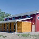 A dark red post-frame equestrian barn