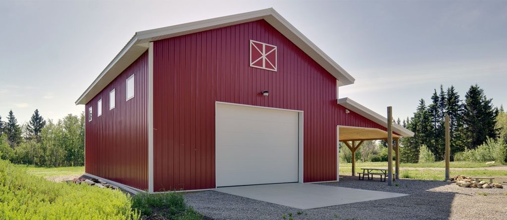 A dark red post-frame equestrian barn