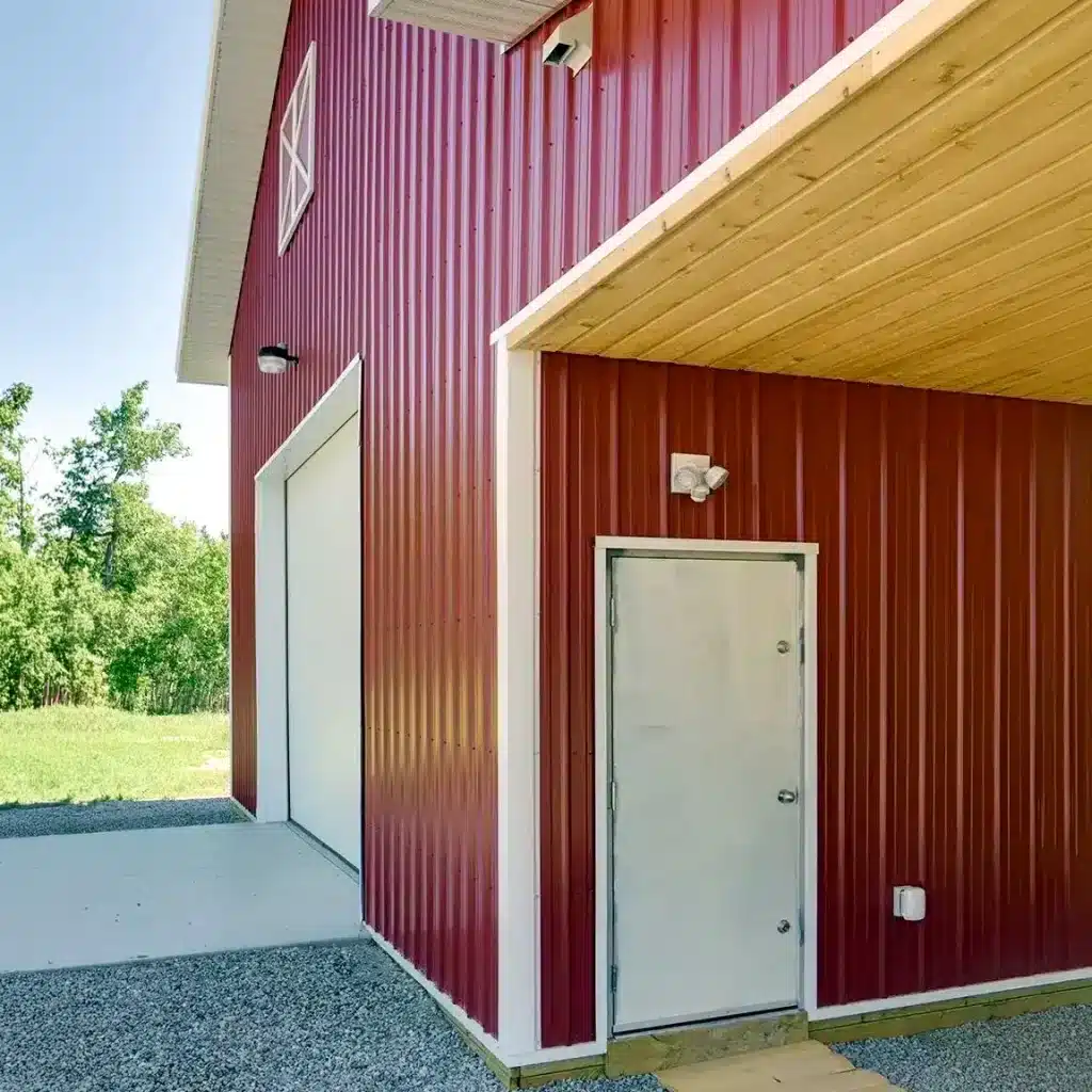 A dark red post-frame equestrian barn