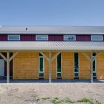 A dark red post-frame equestrian barn